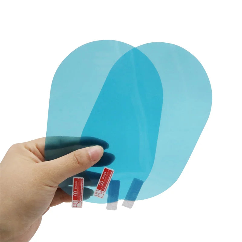 A hand holding two translucent blue tempered glass screen protectors with small red and white protective stickers on a plain white background.